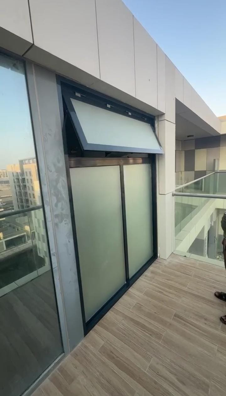 Frosted glass balcony partition with a top-hung awning window open for ventilation in a modern Abu Dhabi villa